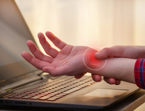 person feels pain in the carpal tunnel while sitting at a laptop