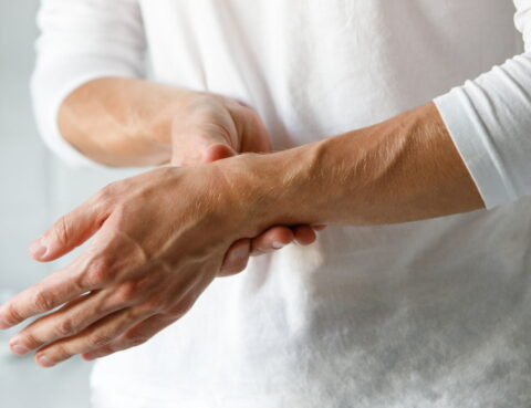 a man holds his hand and feels pain due to nerve damage