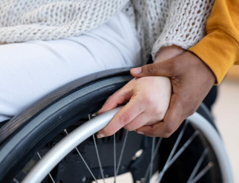 a man helps a patient with ALS to move in a wheelchair