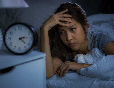 woman is lying in bed and looking at the alarm clock