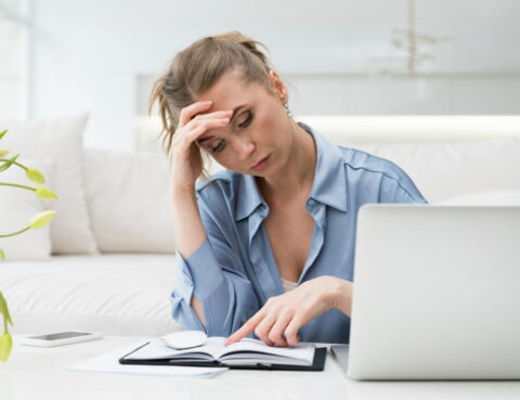 Woman is using laptop and notebook for migraine or headache tracking